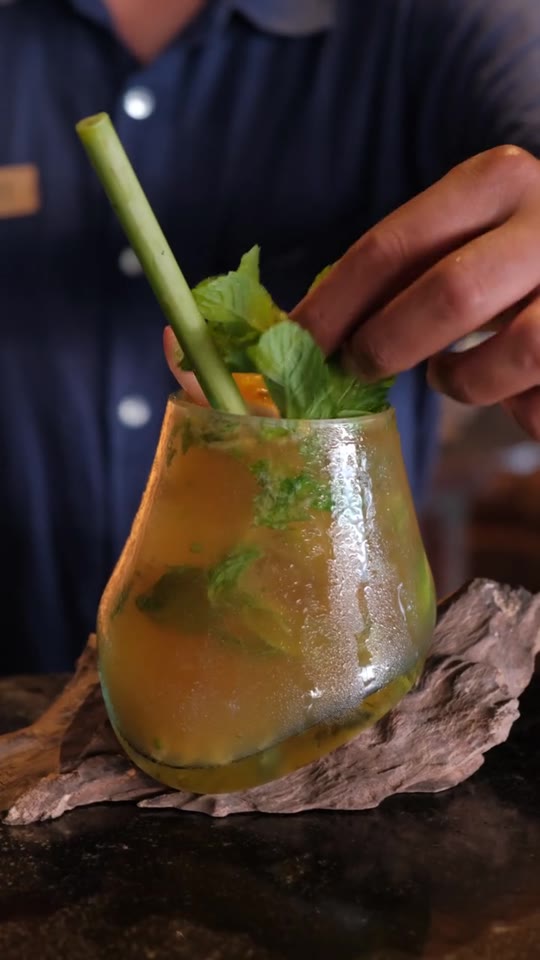 A cocktail being prepared with fruit and herbs
